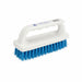 Handy scrubber with blue bristles held by a hand on a wooden surface